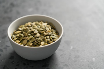 pumpkin seeds in white bowl on terrazzo countertop