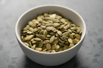 pumpkin seeds in white bowl on terrazzo countertop