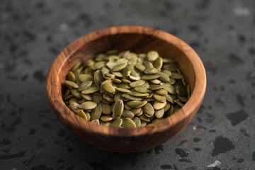 pumpkin seeds in olive bowl on terrazzo countertop