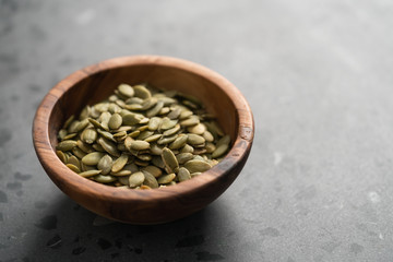 pumpkin seeds in olive bowl on terrazzo countertop