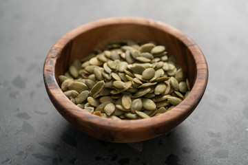 pumpkin seeds in olive bowl on terrazzo countertop