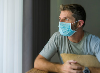 Fototapeta na wymiar covid-19 virus lockdown - sad and worried man in medical mask thinking and feeling scared in quarantine following stay at home instructions to contain virus pandemic