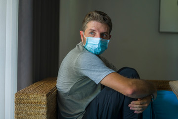 covid-19 virus lockdown - sad and worried man in medical mask thinking and feeling scared in...