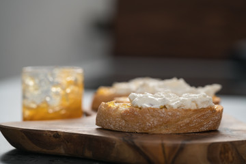 Ciabatta slices with orange marmalade and ricotta on olive board
