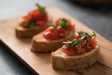 Fototapeta na wymiar bruschetta with cherry tomatoes and spinach leaves on olive board
