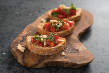 bruschetta with cherry tomatoes, spinach leaves and hard cheese on olive board