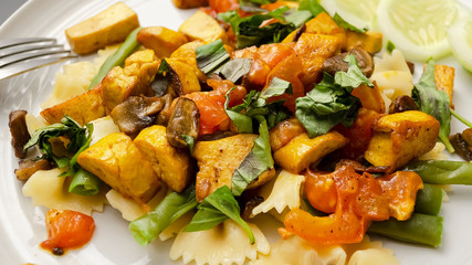 Vegetarian salad with pasta and tofu on a white plate close-up. Healthy and tasty food