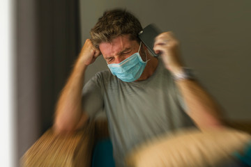 covid-19 virus lockdown - sad and worried man in medical mask thinking and feeling scared in quarantine following stay at home instructions to contain virus pandemic