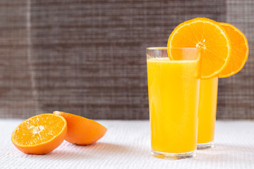 Orange juice in a glass with orange decoration, the best start to the day. Photo on a dark background.