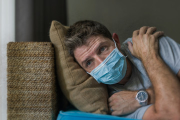 covid-19 virus lockdown - sad and worried man in medical mask thinking and feeling scared in...
