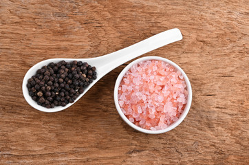 Obraz na płótnie Canvas bowl of pink himalayan salt , Black pepperon wooden table, top view