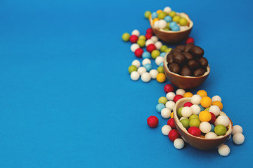 broken chocolate easter eggs and strew colored sweets on blue background