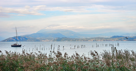Sailboat at Lake Garda under dramatic Sky with beautiful light in the early mornung hours