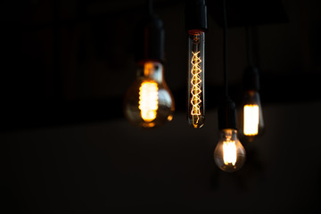 Bare bulb. Worm bokeh lights and dark background. Analog life. Vintage styled tungsten lamp in the...