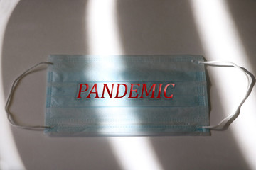 Dramatic atmosphere with surgical mask. Inscription PANDEMIC on a medical mask. Global pandemic alert.