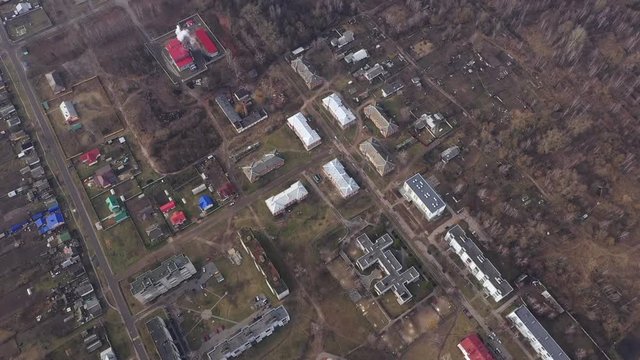 Aerial video of the village. The road goes around the village. Farm field near the village. Village street with multi-story and small houses, outbuildings and household plots in early spring.