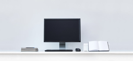 Clean white desk with computer and notebooks.
