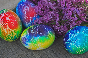 Art decorated eggs with lilac on wooden background.