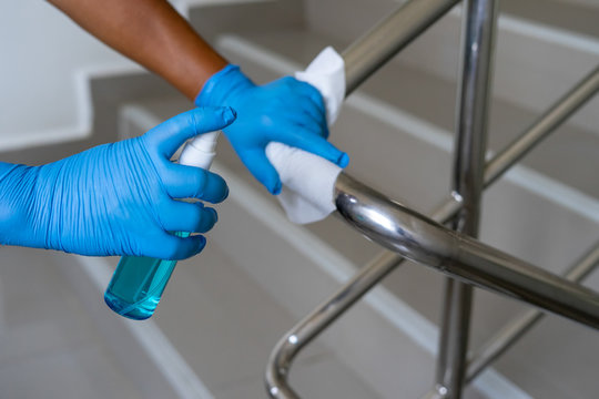 Close Up Of Female Hand Using Wet Wipe And Hand Sanitizer Spray To Clean Stainless Steel Staircase Railing.Antiseptic,disinfection ,cleanliness And Healthcare,anti Virus Concept.Anti Bacterial And Cor