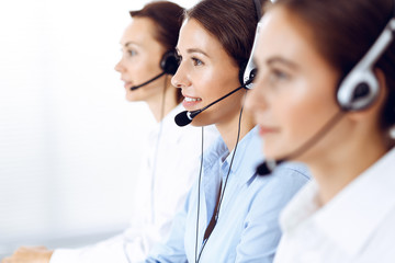 Call center. Group of operators at work. Focus on beautiful business woman in headset