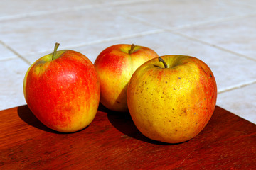 Fresh red organic apples on wooden table in summer day