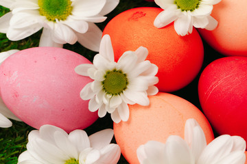 Colored Easter eggs on grass decorated with flowers