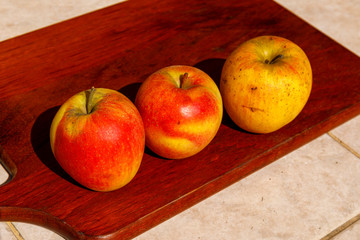 Fresh red organic apples on wooden table in summer day