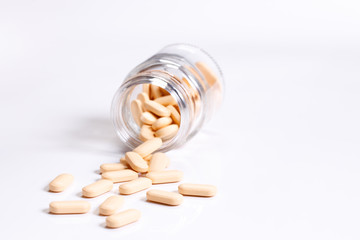 Vitamin tablets in glass bottle on white background