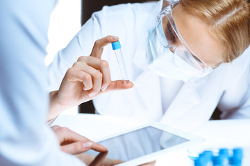 Fototapeta premium Coronavirus pandemic. Professional female scientist in protective eyeglasses researching tube in laboratory. Concepts of medicine and virus protection