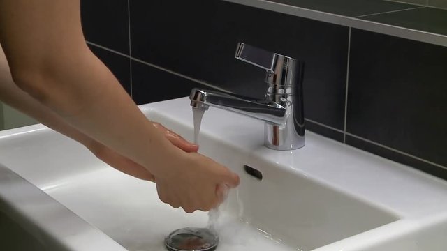 Lavaggio accurato delle mani nel lavandino di casa strofinando bene anche le dita