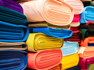 Rolls of bright multicolored fabric close-up. Coils of fabric are on the shelves in the store....