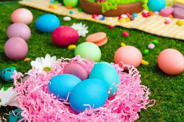 Fototapeta na wymiar Colored eggs and vibrant candies on grass. Easter composition