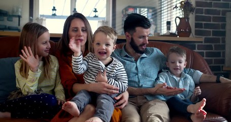 Happy family together, young Caucasian parents and three cute smiling children share bonding time at home slow motion.