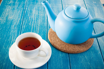 Cup of tea with the blue teapot on the table