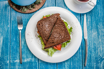 Tasty sandwich with red fish and lettuce on a plate