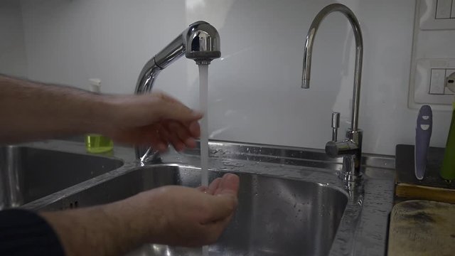 Lavaggio accurato delle mani nel lavandino di casa strofinando bene anche le dita