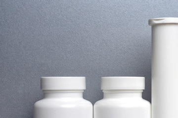 photo of three plastic cans for package pills and vitamins  for protection against coronavirus KOVID-19 on a gray background. photo without bottle labels