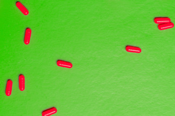 scattering of bright red pills on a green background.