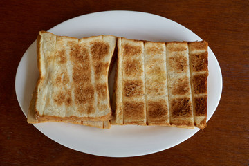 Fried toasts for breakfast on a white plate on a wooden table.  