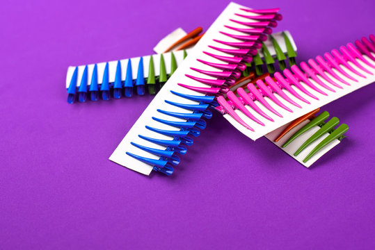 on a purple background hair clips of different colors in sets on a cardboard frame
