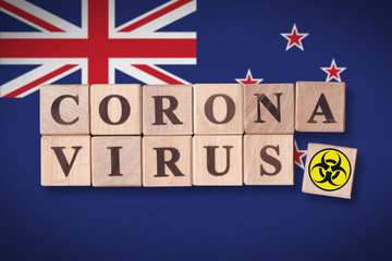 New Zealand flag background and wooden blocks with letters spelling CORONAVIRUS and quarantine symbol on it. Novel Coronavirus (2019-nCoV) concept for an outbreak occurs in New Zealand.