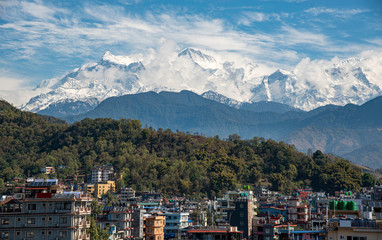 Fototapeta premium The cityscape of Pokhara with the Annapurna mountain range covered in snow at Nepal Asia