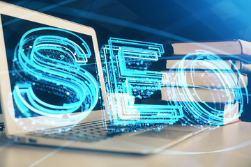 Double exposure of table with computer and seo drawing hologram. Search optimization concept.