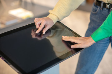 Female hands touching fingers on the screen of the device.