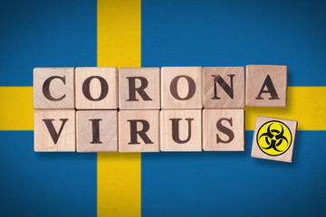 Sweden flag background and wooden blocks with letters spelling CORONAVIRUS and quarantine symbol on it. Novel Coronavirus (2019-nCoV) concept for an outbreak occurs in Sweden.