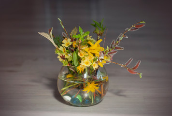 Bouquet of mixed spring flowers and blooming spring flowers in a little glass, round vase.