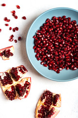 Grains of tasty, bright red peeled pomegranate lie in a plate on a white background. Top view. Close-up.