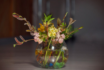 Bouquet of mixed spring flowers and blooming spring flowers in a little glass, round vase.