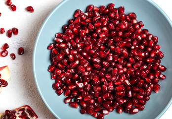 Pomegranate seeds in blue plate. Garnet seeds. Macro shot.