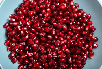 Pomegranate seeds in blue plate. Garnet seeds. Macro shot.